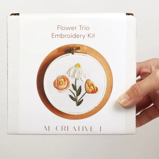 Flower Trio Embroidery Kit packaging held by a hand on a white background. 