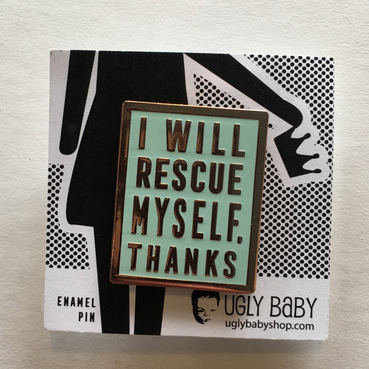 Mint colored rectangular enamel pin that says "I will rescue myself, thanks" in rose gold lettering. It is displayed on a black and white backing card. 