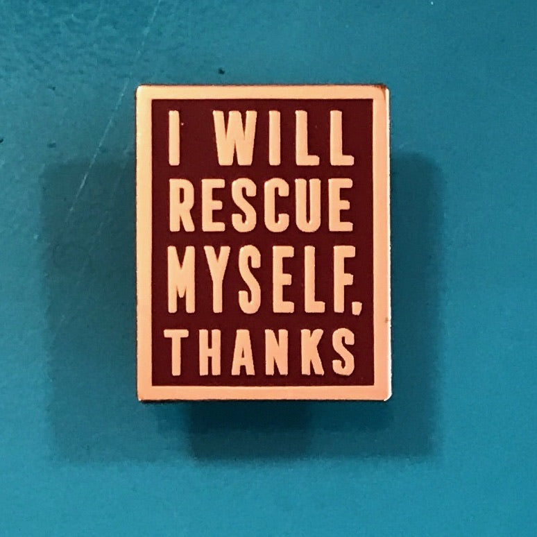 Maroon enamel pin with rose gold text that says I Will Rescue Myself, Thanks against a teal background. 