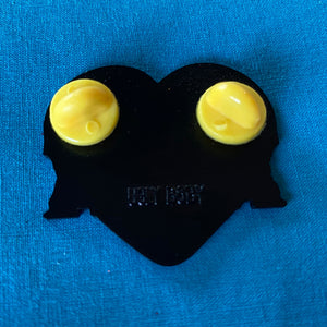 The back of a heart shaped enamel pin with two yellow rubber stoppers.