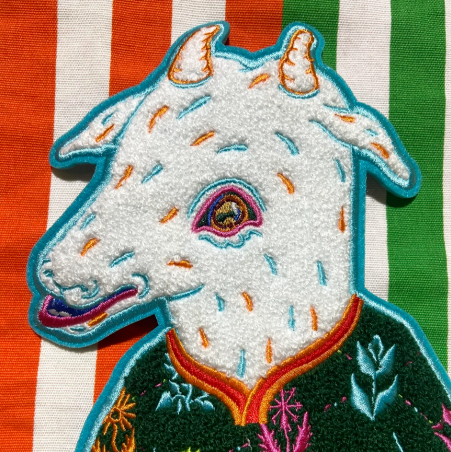 Embroidered patch of a goat's head on a striped fabric background