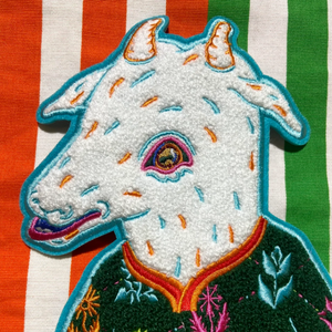 Embroidered patch of a goat's head on a striped fabric background