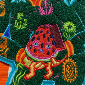 Colorful embroidered patch of a watermelon character with a green background.
