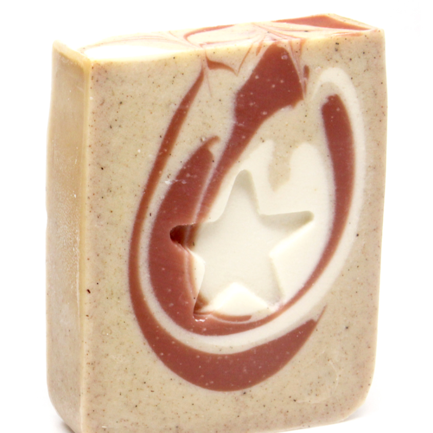 A bar of handmade soap with a beige base and swirled patterns of darker and lighter peach shades, featuring a star shape on top.