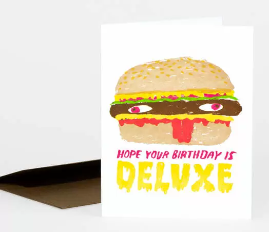A birthday card that says "Hope your birthday is deluxe" and has a cheeseburger with weird eyeballs and a sesame seed bun. 
