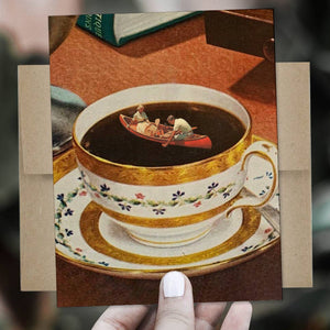 Teacup with miniature boat and figures on a saucer, held by a hand against a blurred background.