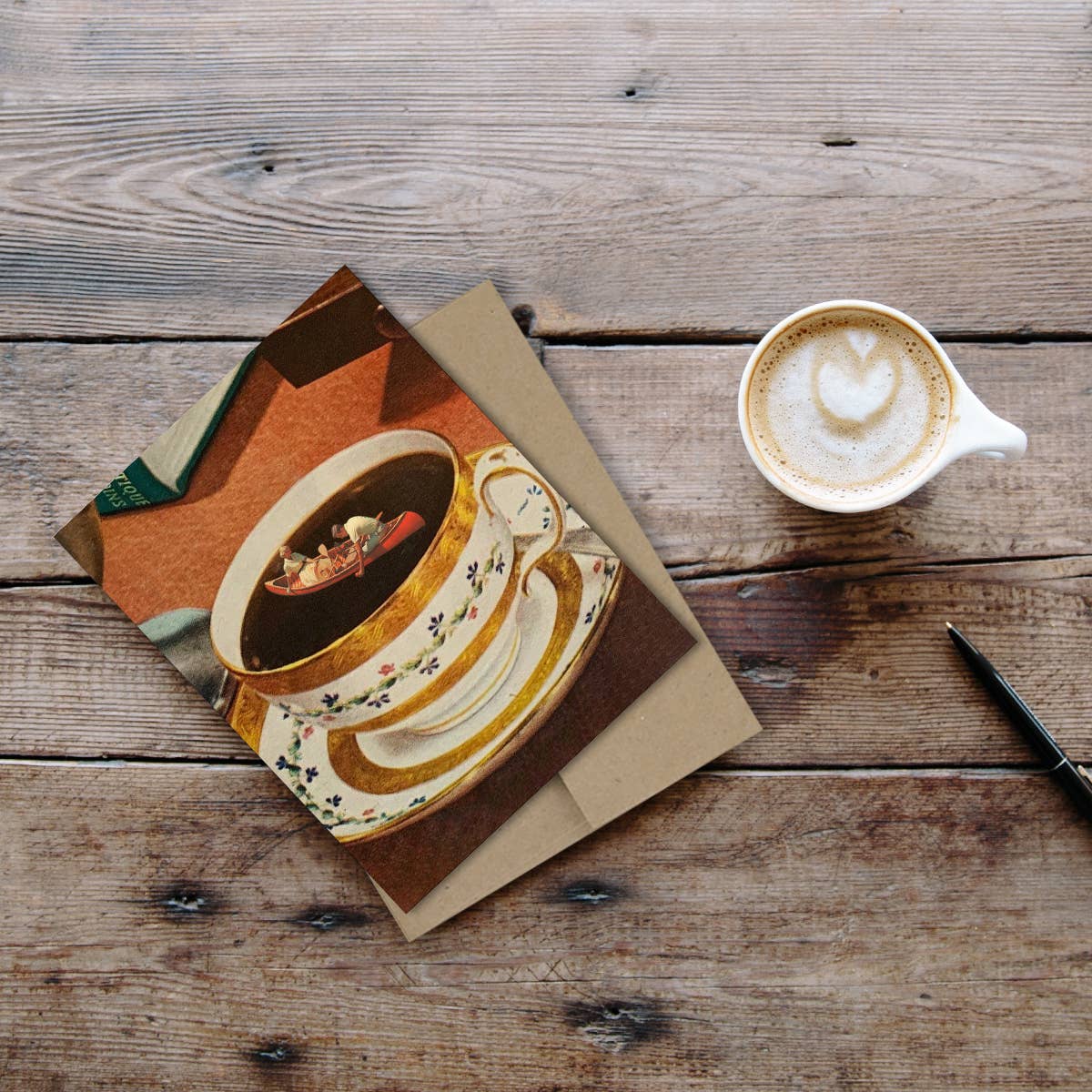 Café au lait with latte art on a wooden surface next to a card with a coffee design.