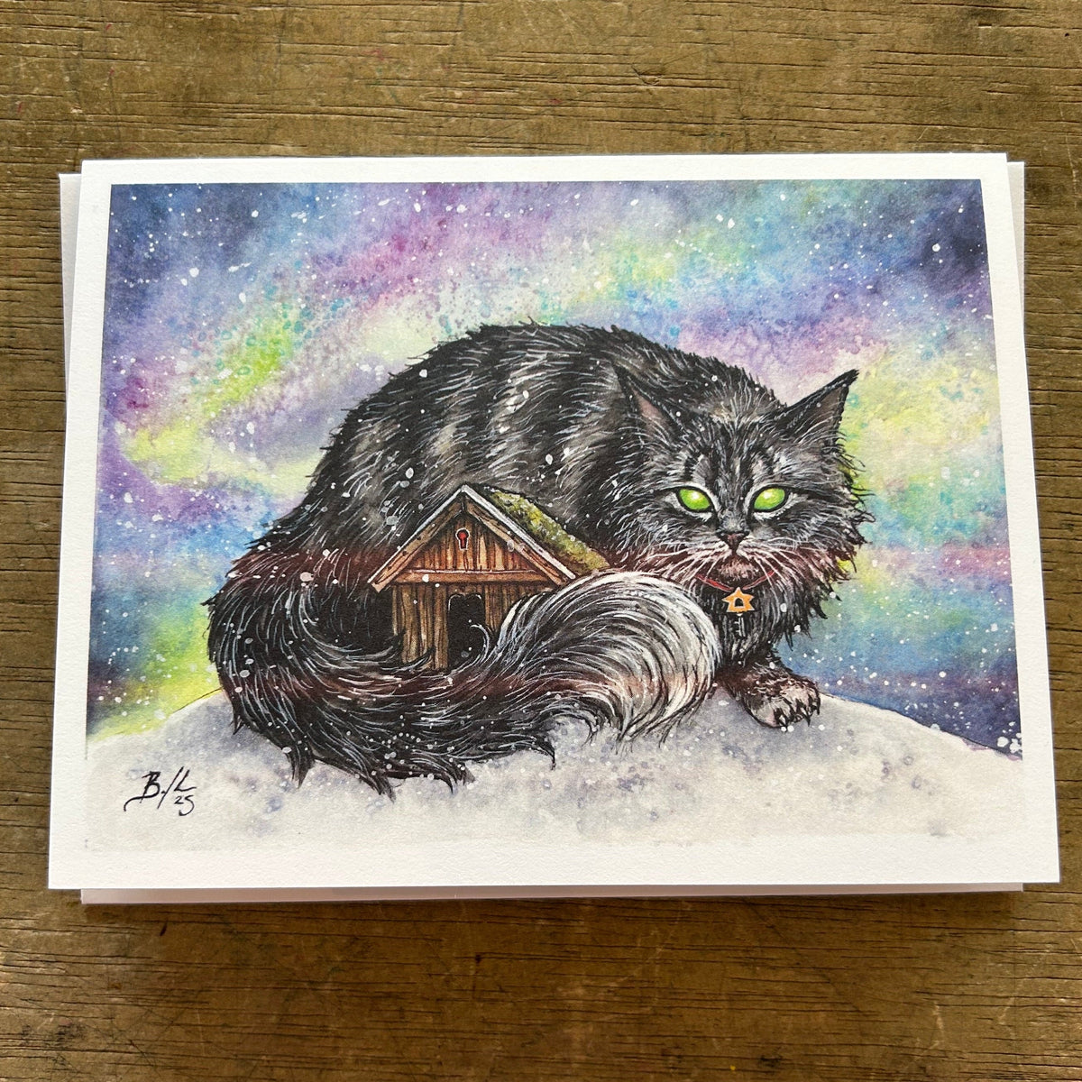 Card with a cat and small house illustration on a wooden surface