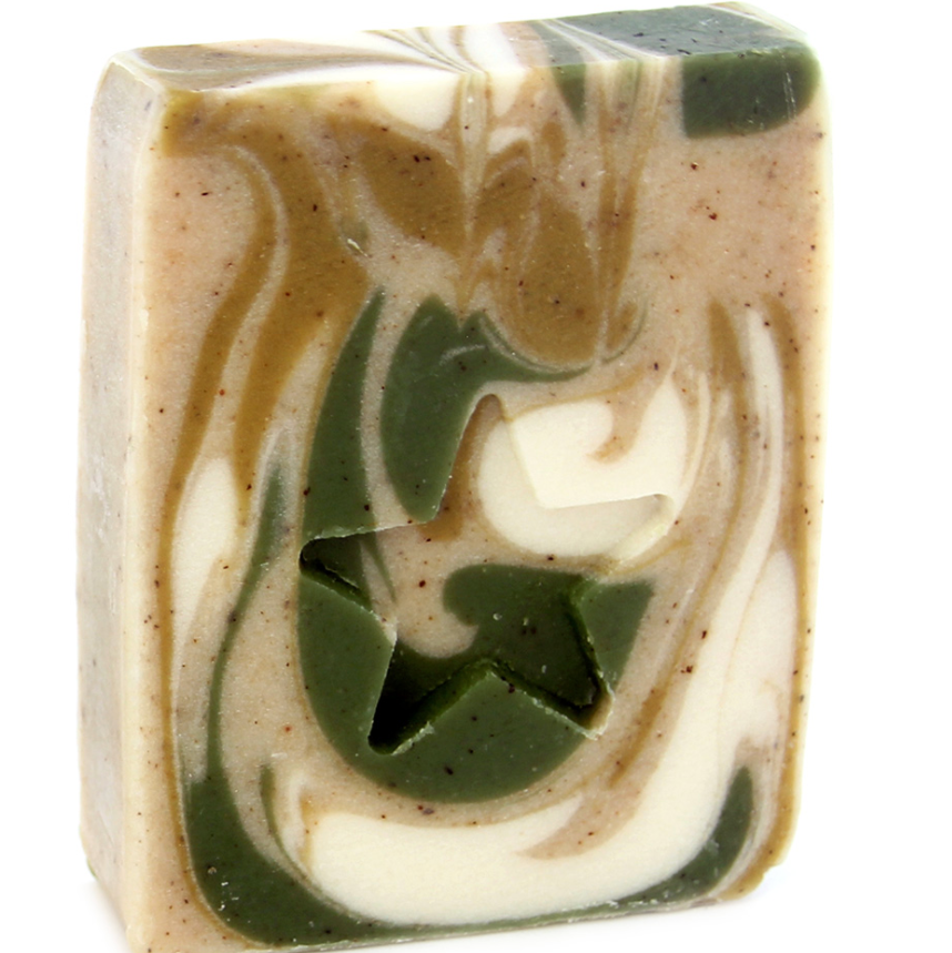 A bar of handmade soap with a swirl pattern featuring beige, green, and white colors, with exfoliating bits visible on the surface.