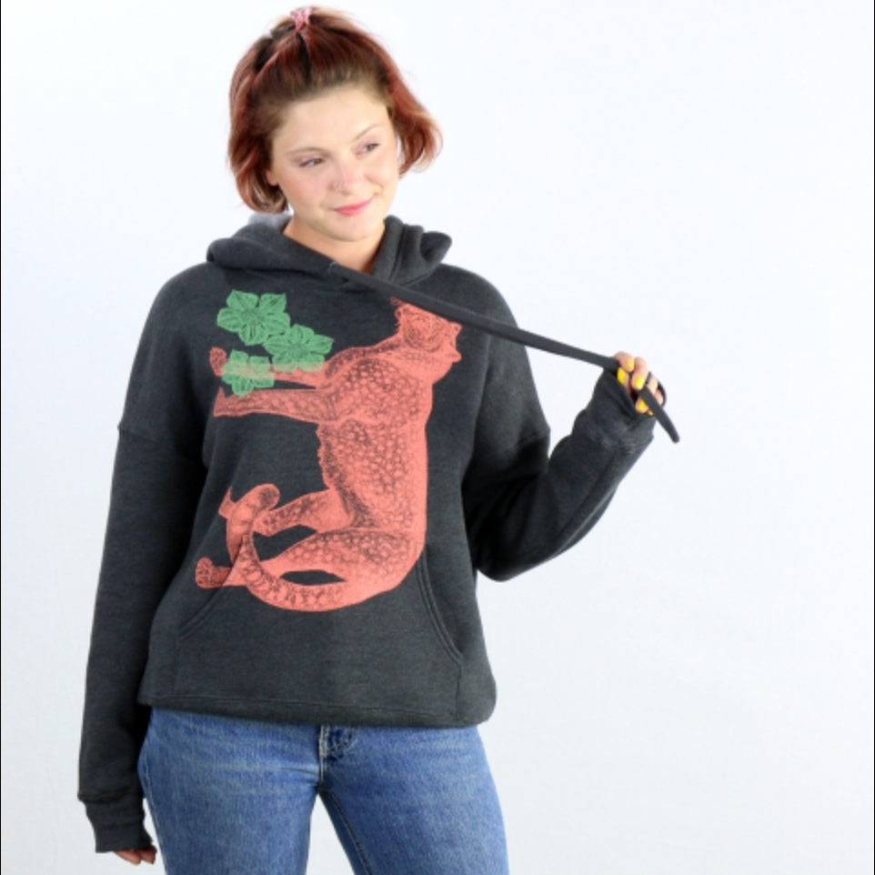 Person wearing a black hoodie with an orange cheetah design on a white background. 