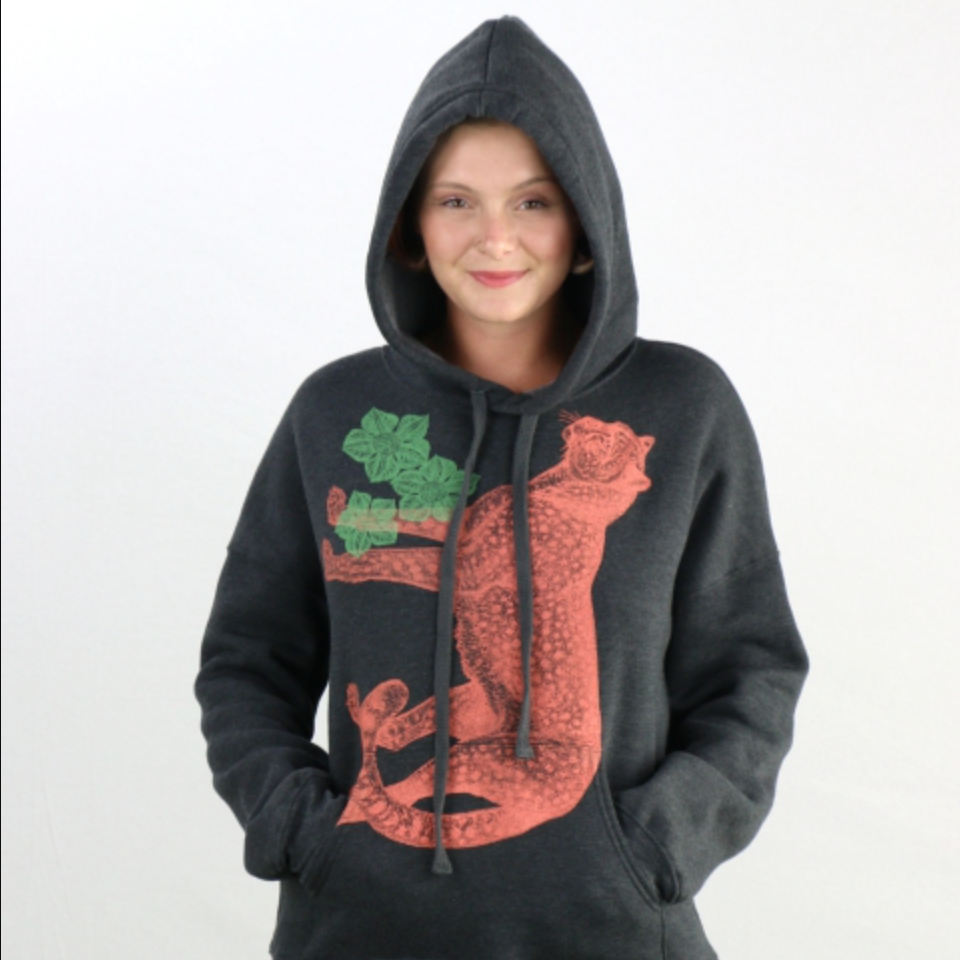 Person wearing a dark gray hoodie with orange and green designs on a white background