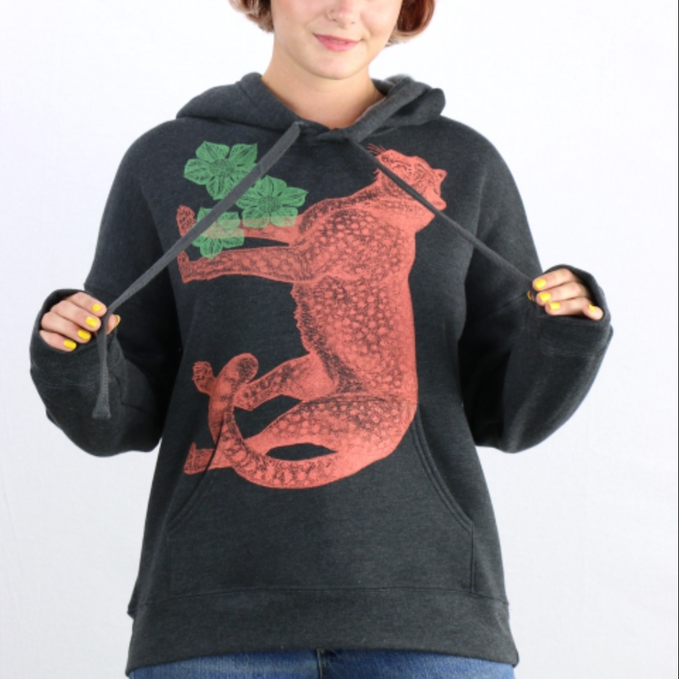 Person wearing a black hoodie with an orange cheetah design and green leaves on a white background. 