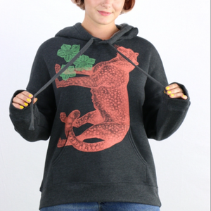 Person wearing a black hoodie with an orange cheetah design and green leaves on a white background. 