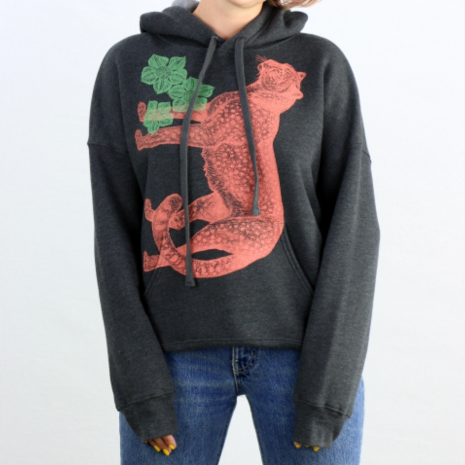 Person wearing a dark gray hoodie with an orange cheetah design on a white background. 