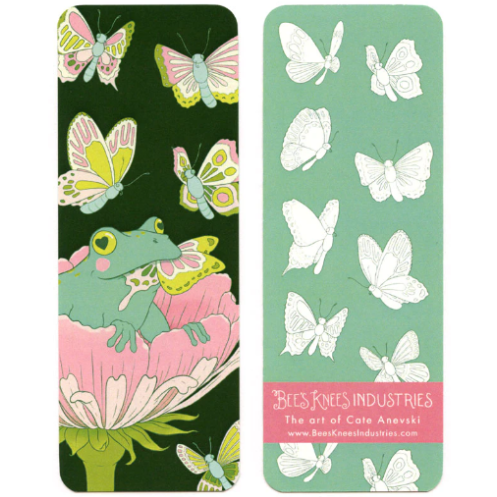 A bookmark with a frog sitting in a flower eating a butterfly on one side and white butterflies against a green background on the other. 
