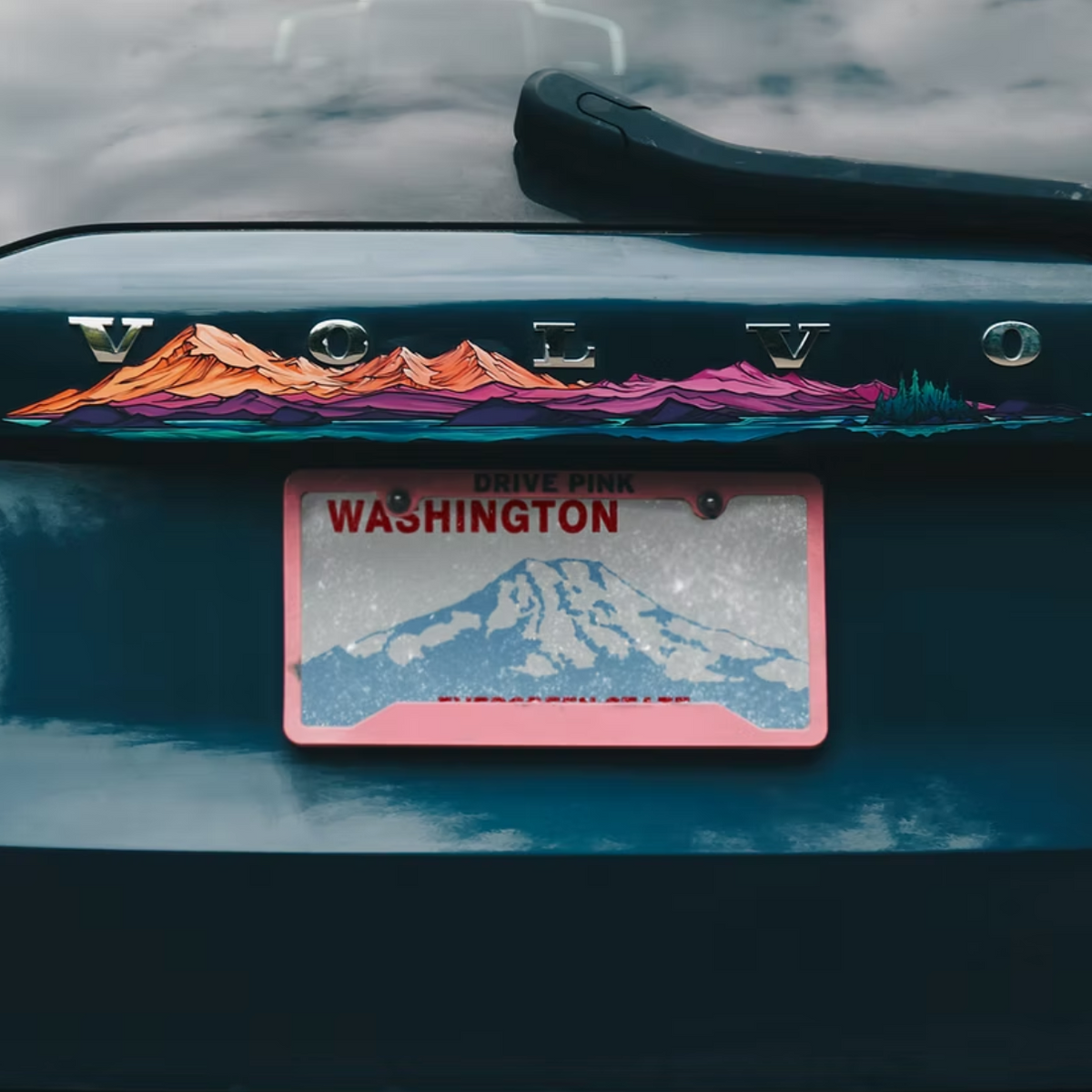 Car with a colorful Mt. Baker and Twin Sisters mountain design sticker on the trunk and a 'Washington' license plate.
