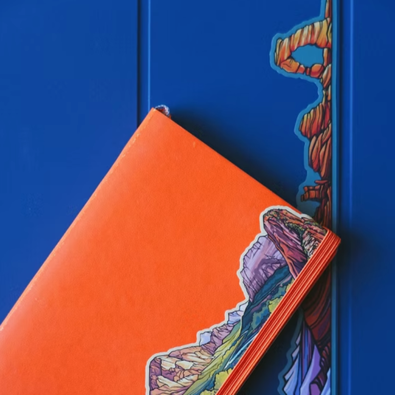 Orange notebook with an Arches mountain design on a blue background.
