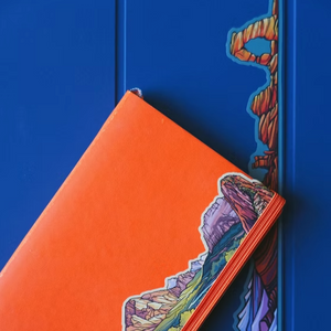 Orange notebook with an Arches mountain design on a blue background.