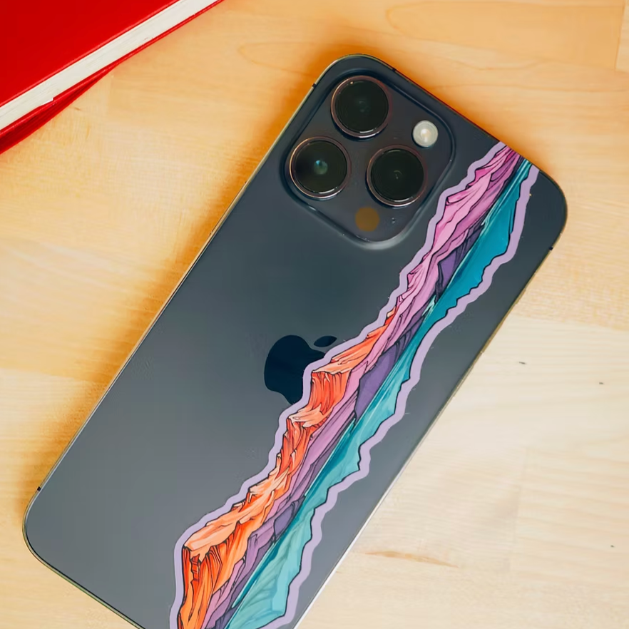 Phone case with Mt. Baker & Twin Sisters infinity sticker design on a wooden surface.