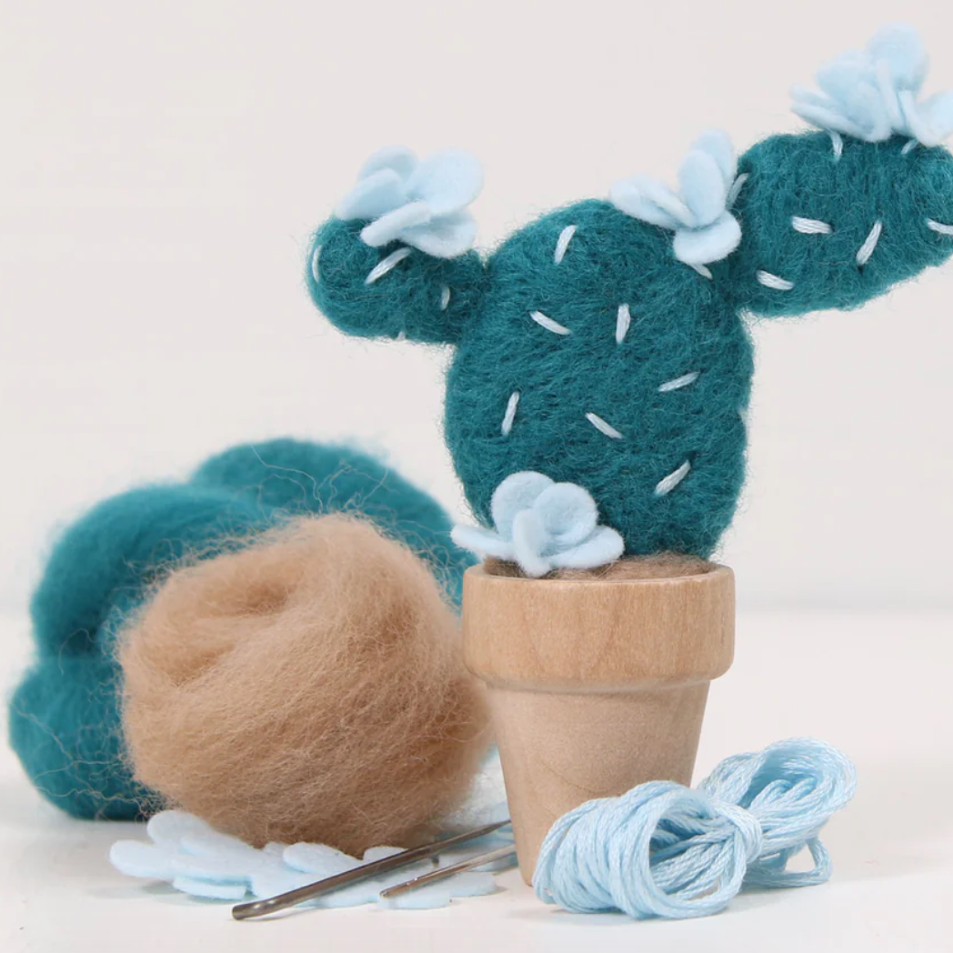 Needle felted cactus plant with wool roving and needle felting tools on a light background