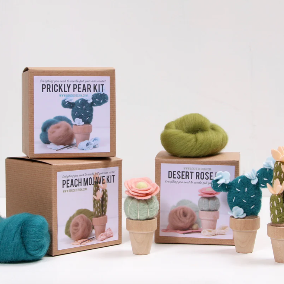 Needle felted cactus kits and wool roving on a white background.
