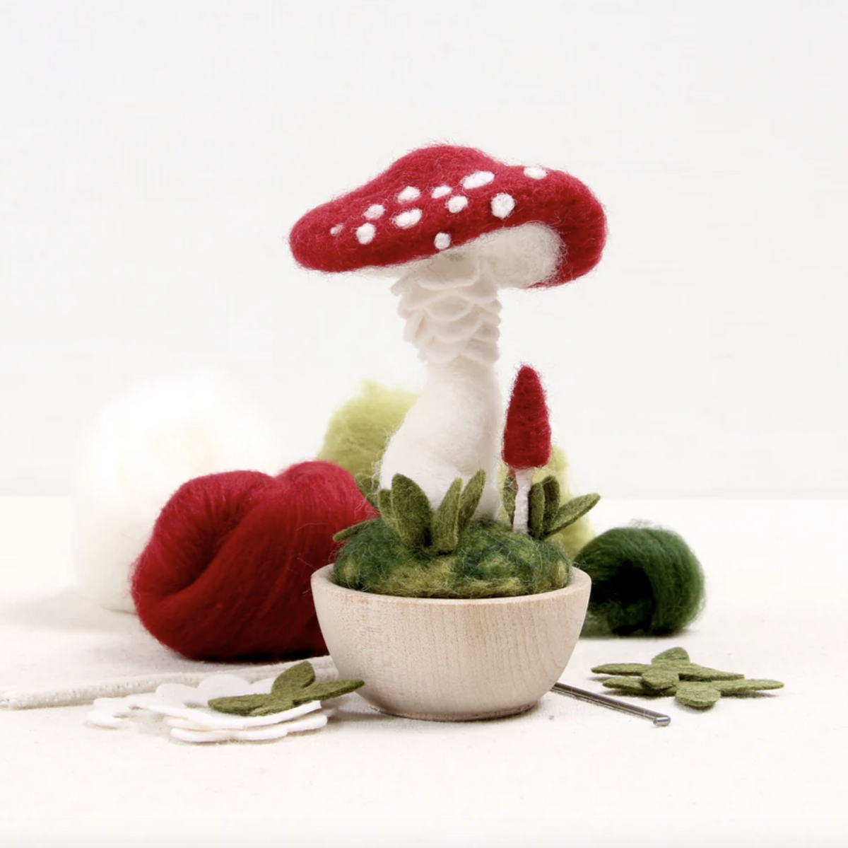 Needle Felting Kit to create a Crimson Toadstool mushroom. This photo shows the finished product of a felted mushroom in a little wooden cup. 