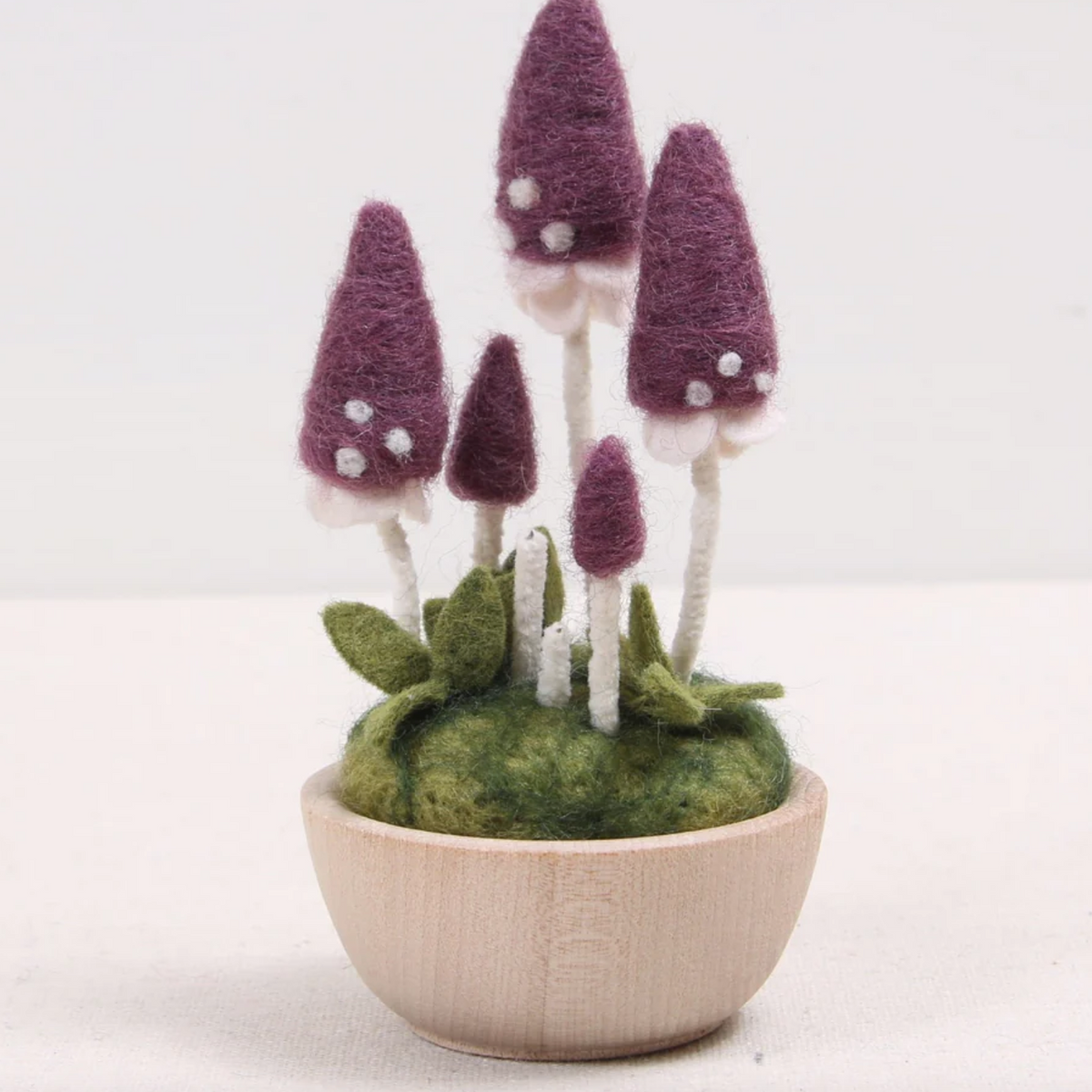 Completed Pink Parasol Needle Felted mushroom kit displayed in a little wood cup against a white background.