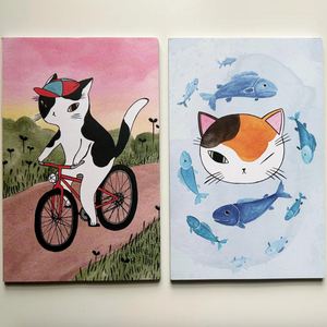 Two illustrated cards featuring a cat on a bike and a cat among fish, on a white background.