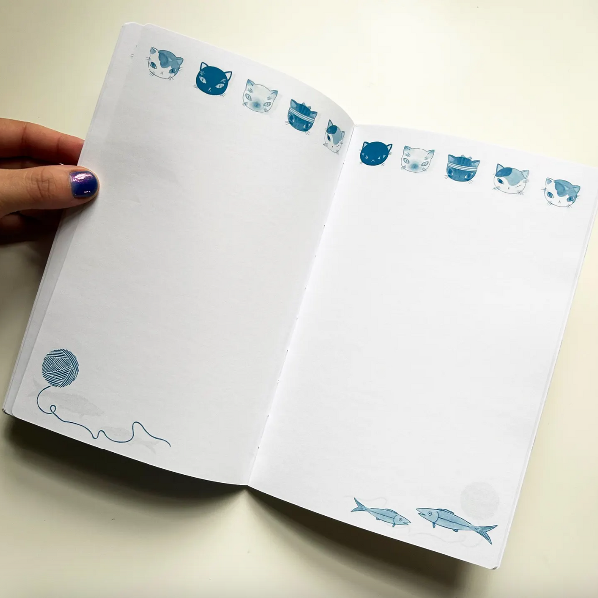 Open notebook with blue cat illustrations on a light background.