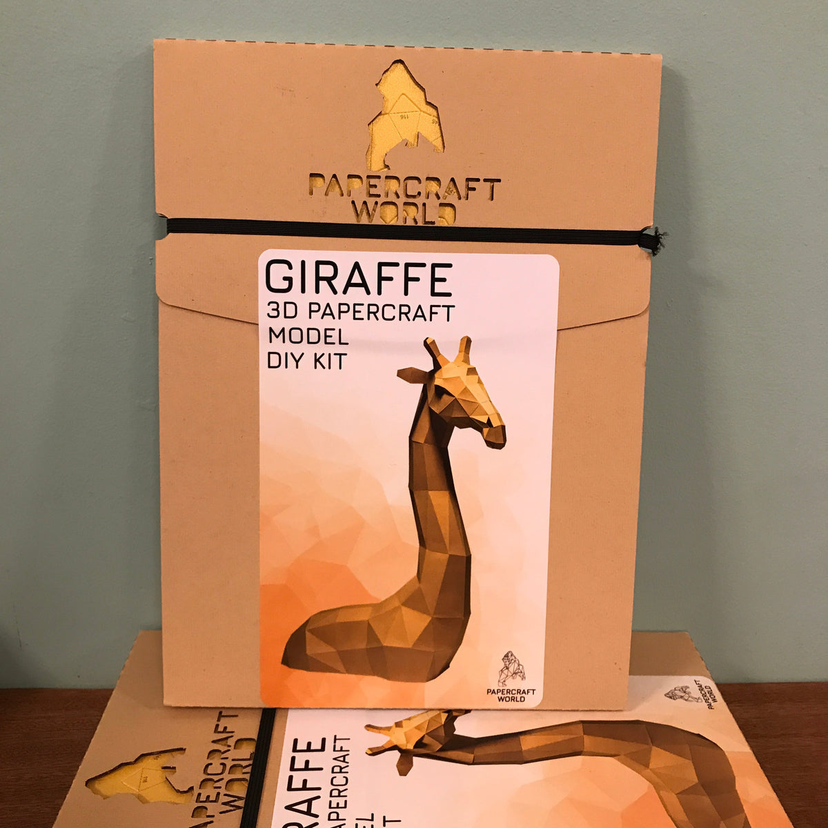 Packaging for a giraffe paper craft kit. A completed example of a giraffe paper craft kit against a white background is on the front.