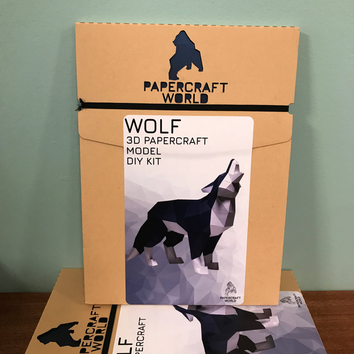 Packaging for the wolf paper craft kit. It is brown kraft paper with the papercraft world logo laser cut into the top.