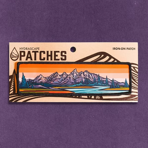 Iron-on patch with mountain landscape design on a purple background. 