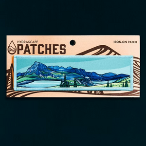 Iron-on patch with mountain landscape design on a Hydrascape Patches card.