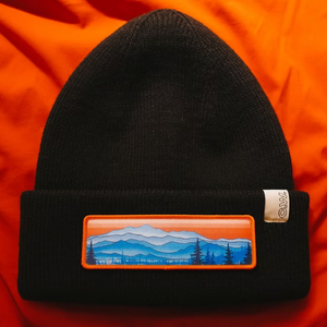 Black beanie with an Appalacian Mountain scenic patch on an orange background