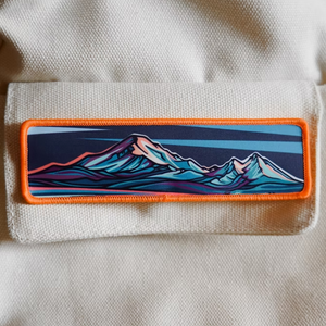 Mountain-themed patch on a beige background