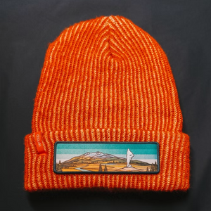 Orange knit beanie with a Yellowstone mountain patch on a black background