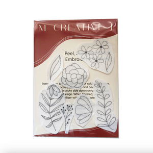 Packaging of MCreativeJ peel, stick & stitch embroidery supply with floral designs on a white background. 