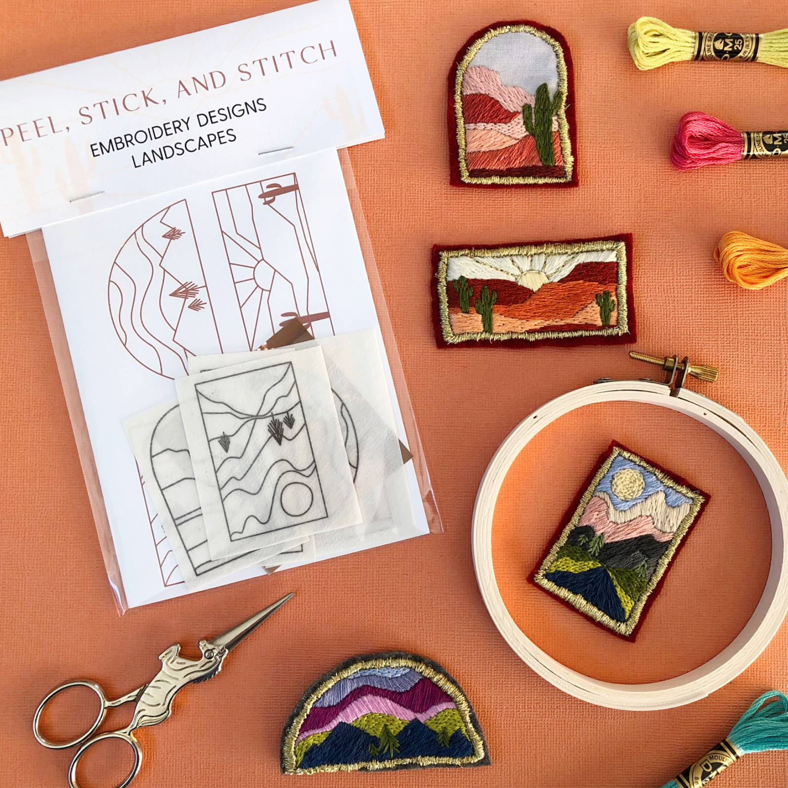 Embroidery designs with landscapes, embroidery hoop, scissors, and thread on a peach background. 