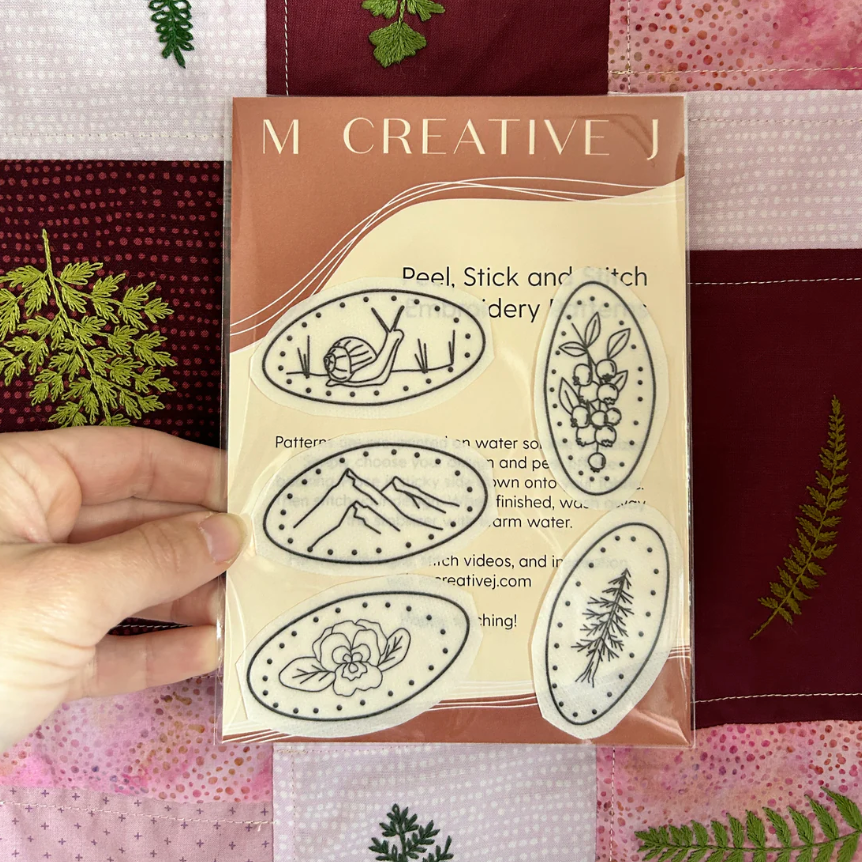Package of peel, stick, and patch craft material with nature-themed designs on a checkered fabric background.