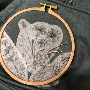Embroidery hoop with floral design on a dark fabric background. 