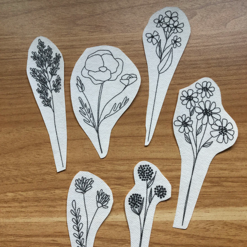 White cut-out shapes with black floral patterns on a wooden surface. 