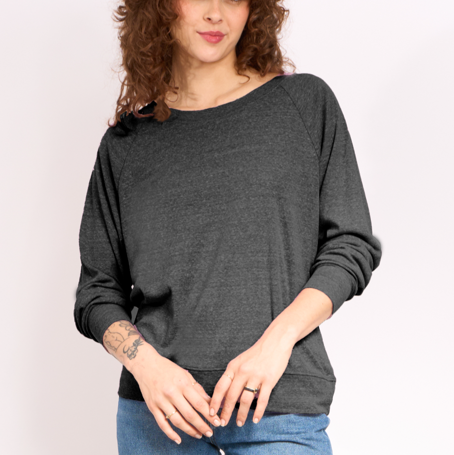 Woman wearing a dark gray long-sleeve top and blue jeans against a light background
