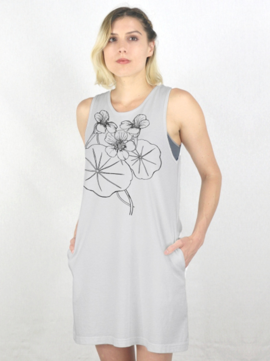 A woman modeling a sleeveless french gray shift dress with a black line art graphic of nasturtiums and leaves on the front, set against a plain white studio background.