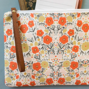 Floral patterned pouch with a brown zipper on a gray surface
