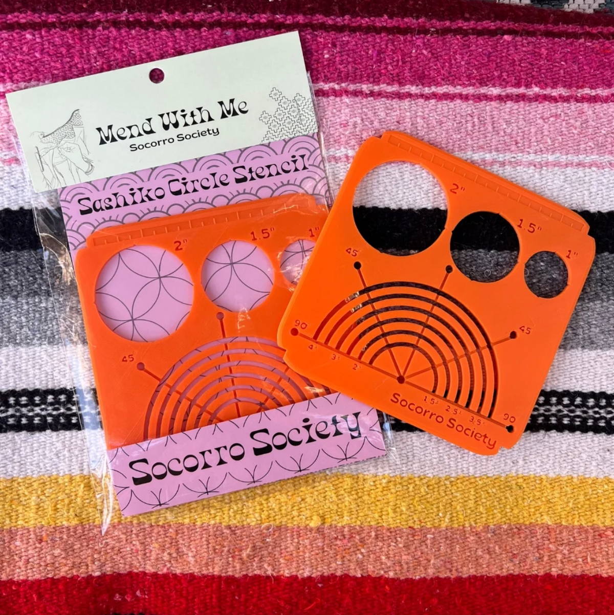Orange Sashiko circle stencils with packaging on a striped fabric background. 