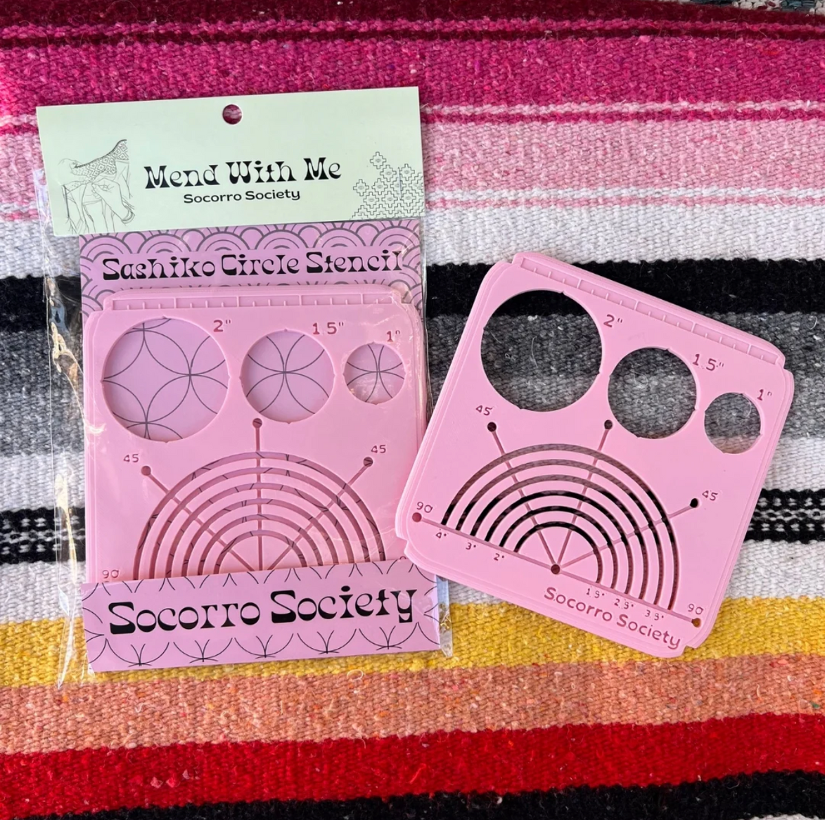 Pink sashiko circle stencils with packaging on a colorful striped fabric background. 
