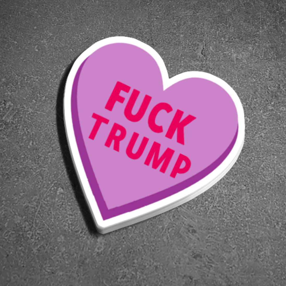 Pink heart-shaped sticker with 'FUCK TRUMP' text on a gray background