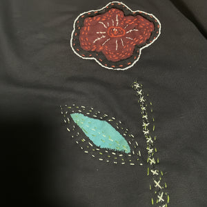 Reverse applique flower design on a dark fabric background. 