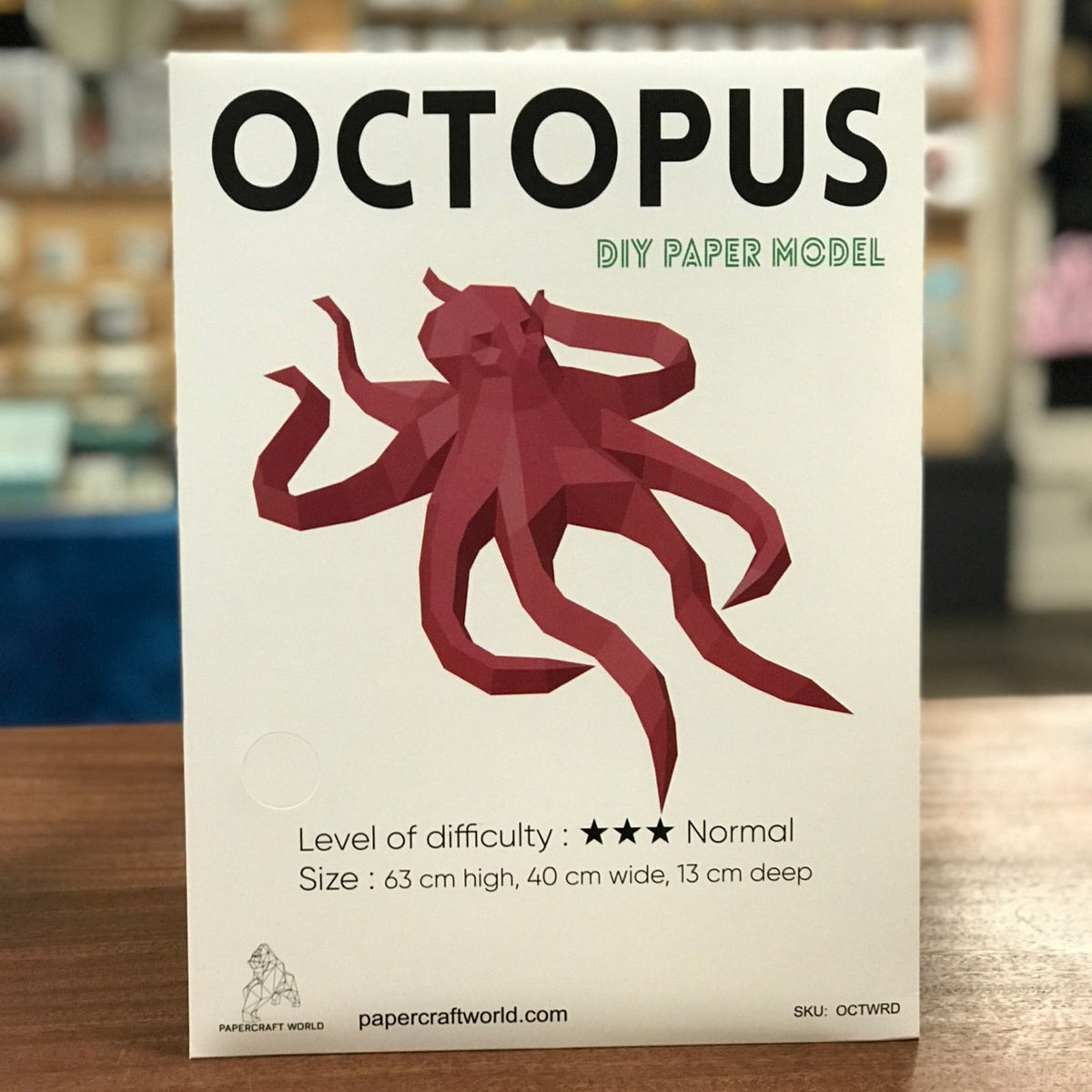 Packaging for the octopus paper craft kit. It says "Octopus" in big black capitol letters and has a white background. A photo of a completed octopus craft kit is shown on the front. 