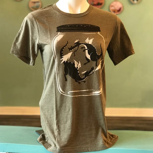 A shirt on a mannequin that shows two dragons with wings captured in a jar. Dragonflies. 